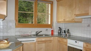 Una cucina con mobili in legno, una finestra, un lavello e una lavastoviglie.