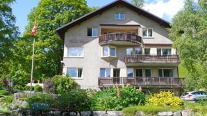 Un edificio a più piani con balconi, una bandiera e un muro in pietra di fronte.