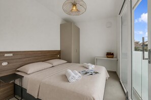 Ein modernes Schlafzimmer mit Bett, Nachttischen, einer Stehlampe und Blick durch eine Glastür.