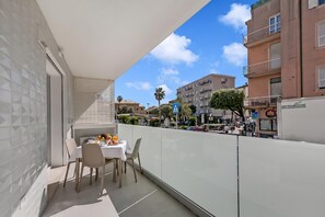 Ein Balkon mit Tisch und Stühlen, Blick auf die Straße und Gebäude im Hintergrund.
