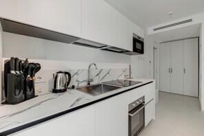 Eine moderne Küche mit Marmorarbeitsplatte, Edelstahlgeräten und einem eingebauten Backofen.