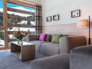 A modern living room with a sofa, a coffee table, and a view of a snowy mountain landscape through large windows. - Turrabuel Appartement/Fewo Turrabuel 3-Zimmer Deluxe by Interhome (Parpan)