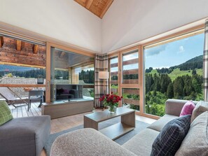 A spacious living area with a large window, a flat-screen TV, and a comfortable seating arrangement. - Turrabuel Appartement/Fewo Turrabuel 3-Zimmer Deluxe by Interhome (Parpan)