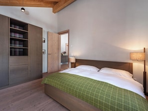 A bedroom with a bed, a wardrobe, and a nightstand. - Turrabuel Appartement/Fewo Turrabuel 3-Zimmer Deluxe by Interhome (Parpan)