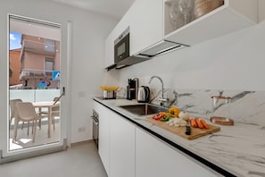 Uma cozinha moderna com bancada de mármore, forno embutido e área de refeições com cadeiras e mesa.