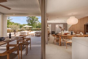 A modern dining area with a view of a garden and pool. - Nareo Villa Collection - Villa Orla, Labin, Croatia (Labin)