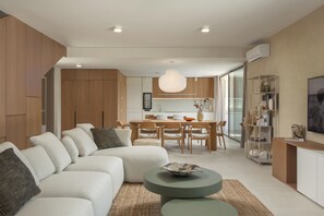 Ein modernes Wohnzimmer mit einer Couch, Essbereich und einer Küche im Hintergrund.