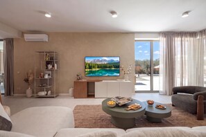 A modern living room with a flat-screen TV, a sofa, a coffee table, and a bookshelf. - Nareo Villa Collection - Villa Orla, Labin, Croatia (Labin)