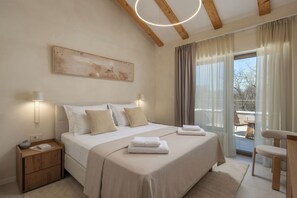 Ein Schlafzimmer mit Bett, Nachttischen, einem Gemälde und Blick ins Freie.