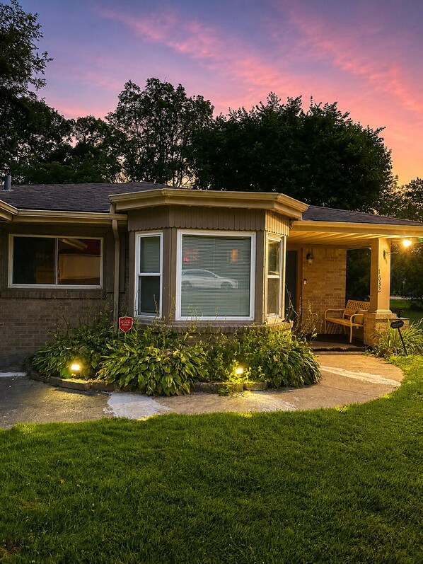 A two-story house with a covered porch and a small garden. - Luxury Garden Retreat • King Bed • Near Anderson Gardens (Rockford)