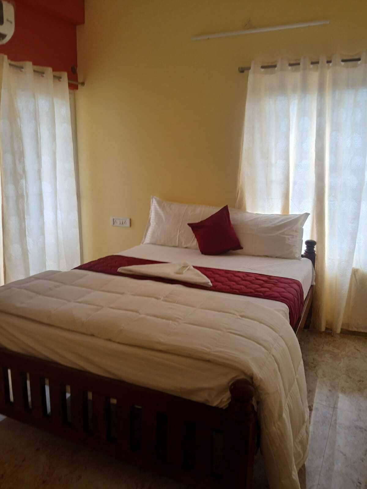A bedroom with a bed, curtains, and a wall socket.