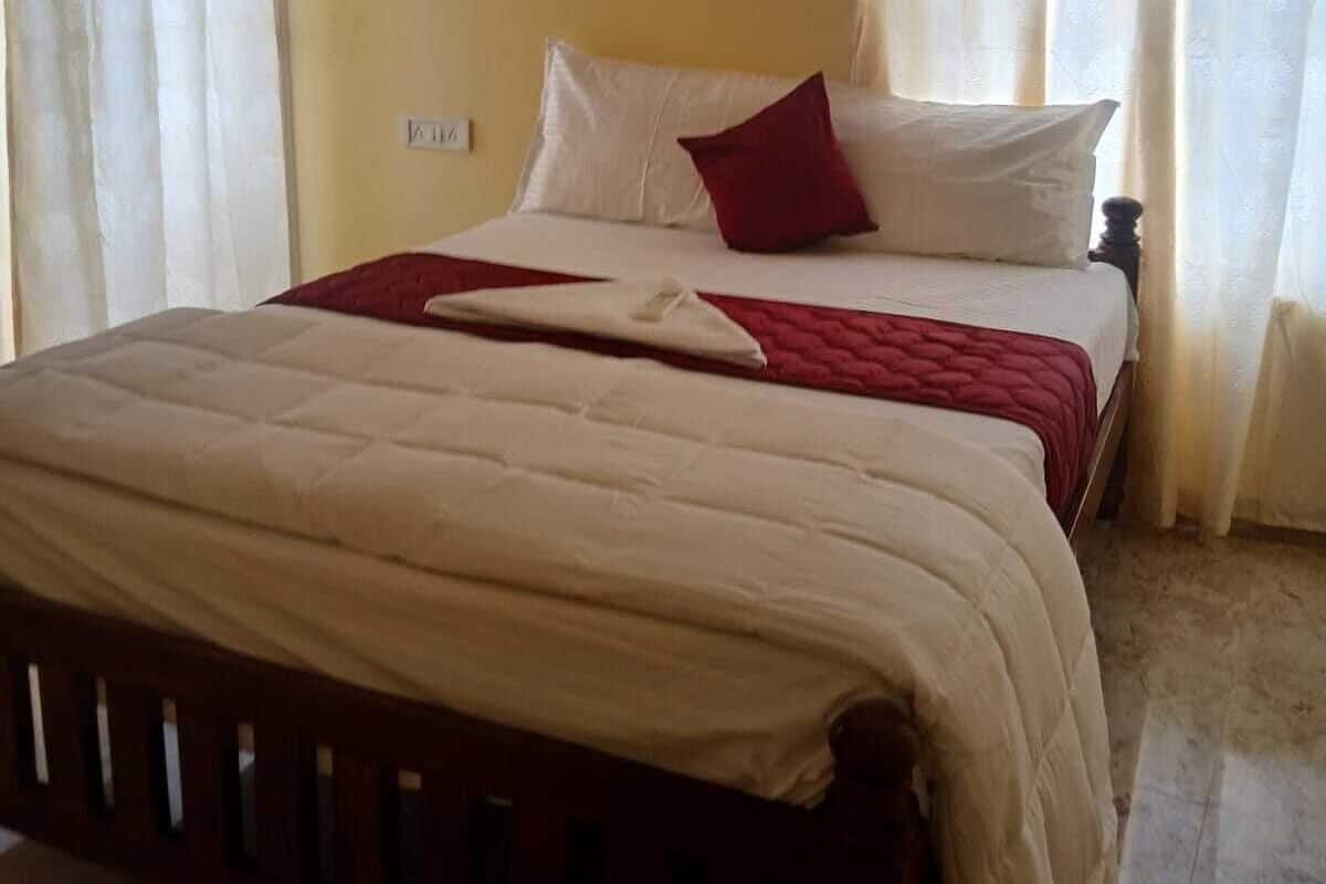 A bedroom with a bed, curtains, and a wall socket.