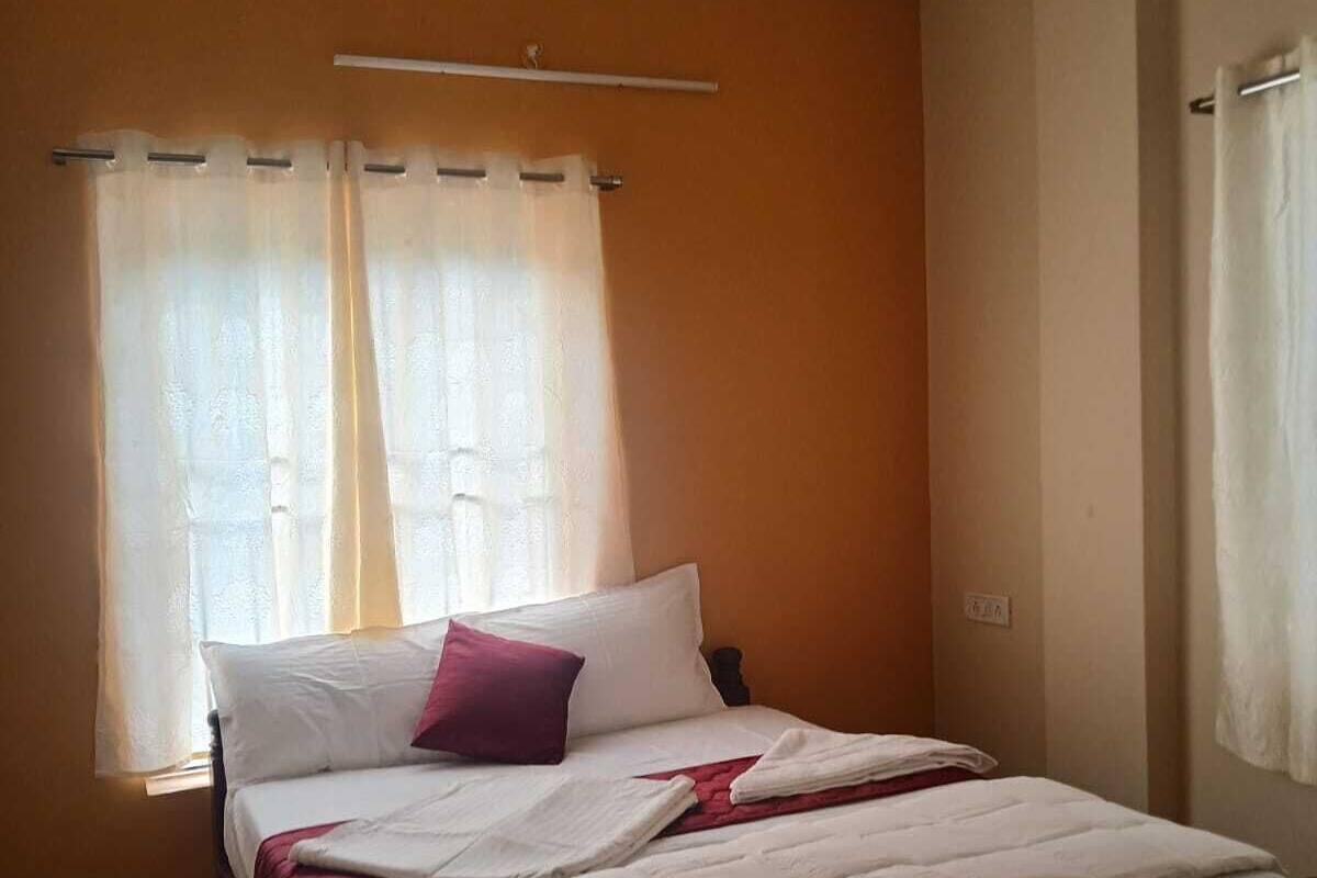 Un dormitorio con cama, ventilador de techo y ventana con cortinas.
