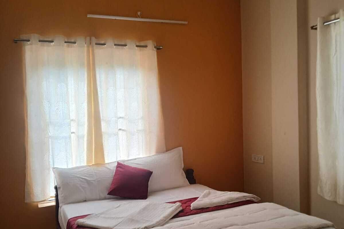A bedroom with a bed, a ceiling fan, and a window with curtains.