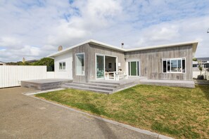 Et moderne hus i to etager med fladt tag, store vinduer og en veranda.