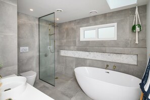Un baño moderno con una bañera independiente, una ducha con mampara de vidrio y un inodoro.