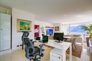 A modern office space with a desk, chairs, a TV, and a view of the mountains. - Panoramic Lugano Loft 8min walk to center, Lugano, Switzerland (Lugano)
