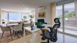 Moderni hotellihuone, jossa on ruokailutila, kannettava tietokone, tuoli ja näkymä ulos.