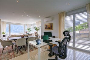 A modern hotel room with a dining area, a laptop, a chair, and a view of the outdoors. - Panoramic Lugano Loft 8min walk to center, Lugano, Switzerland (Lugano)
