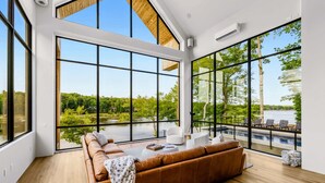 Ein modernes Wohnzimmer mit großem Fenster, Holzbalkendecke und Blick auf einen See.