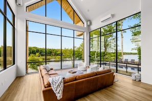 Een moderne woonkamer met een groot raam, een houten plafond en uitzicht op een meer.