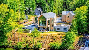 Ein modernes Haus mit einer großen Terrasse, einem Schwimmbad und einer Anlegestelle, die sich in einen See erstreckt.