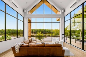 Een moderne woonkamer met een groot raam, een bruine bank en een schaakbord.