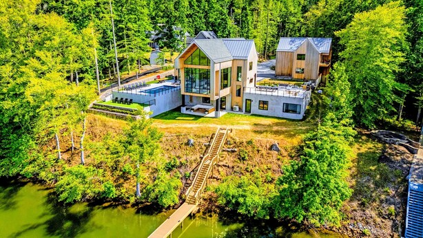Ein modernes Haus mit Schwimmbad, umgeben von dichtem Wald und einem Steg.