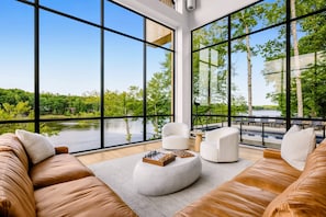 Un salon moderne avec de grandes fenêtres, une cheminée et une vue sur un lac.