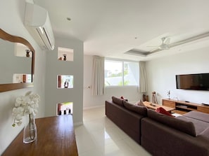 A modern living room with a sofa, TV, and a ceiling fan.