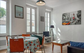 Ein Essbereich mit einem Tisch für zwei Personen, einem Stuhl, einer Lampe und einem Bild an der Wand.