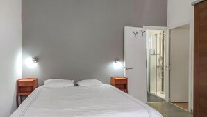 A bedroom with a bed, two bedside tables, a nightstand, a wall-mounted light, and a door leading to a bathroom. - Amazing apartment in La Rochelle with WiFi (La Rochelle)
