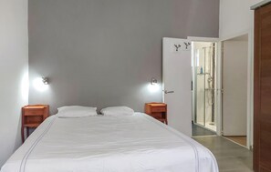 Ein Schlafzimmer mit einem Bett, zwei Nachttischen, einer Wandleuchte und einer Tür zu einem Badezimmer.