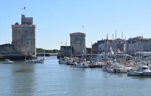Ein Yachthafen mit vertäuten Booten, eine Burg und Gebäude im Hintergrund.