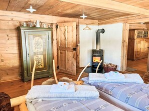 Ein Holzhütten-Interieur mit Kamin, Schrank und zwei Betten.