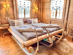A wooden cabin room with a bed, two windows with curtains, and wall-mounted lamps. - Sennhütte Kiental by Interhome (Kiental)