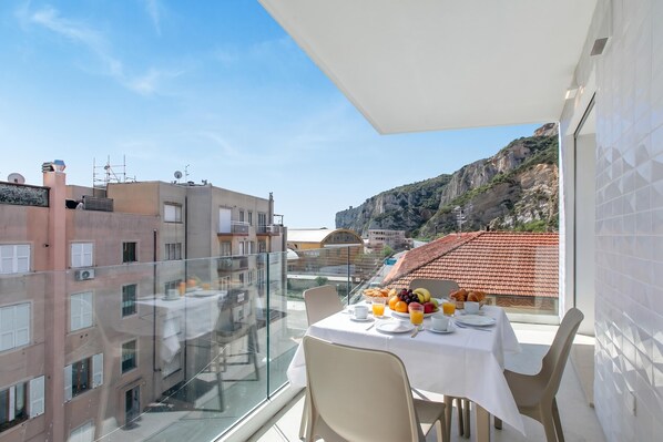 A balcony with a table set for breakfast, overlooking a cityscape and a mountain. - Nua Boutique Apartaments 19 Towncentre, Finale Ligure, Italy (Finale Ligure)
