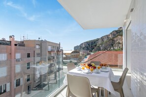 Ein Balkon mit einem Frühstückstisch, mit Blick auf eine Stadtlandschaft und ein Gebirge.