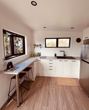A modern kitchen with a countertop, sink, and a window. - The Cabin & Sauna @ The Highlands (Waipu)