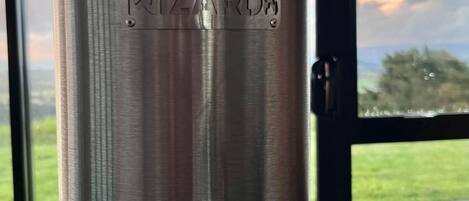 Un objet cylindrique métallique, portant l’inscription « WIZARDS » sur une surface texturée, est placé sur un socle devant lequel on aperçoit une fenêtre.