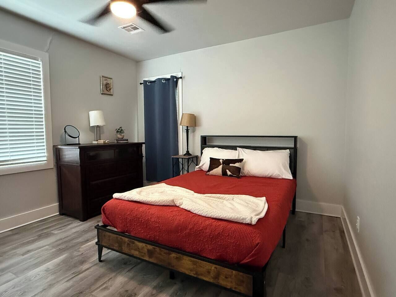 Une chambre à coucher comprenant un lit, une commode, des tables de chevet et un ventilateur de plafond.