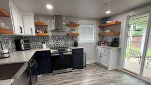 Une cuisine moderne dotée d’un îlot central, d’un four encastré et d’une grande fenêtre donnant sur un patio.