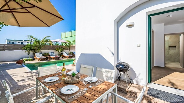Ein Essbereich im Freien mit Pool, Liegestühlen und Grill.