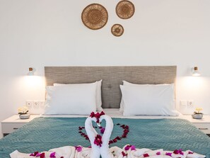 A neatly made bed with white pillows, a teal quilt, and decorative swans made of towels with flowers. - Gemini Villas- Harmony Villa by Interhome (Rhodos City)
