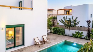 Ein moderner Poolbereich mit klarem Pool, Liegestuhl und kleinem Tisch.