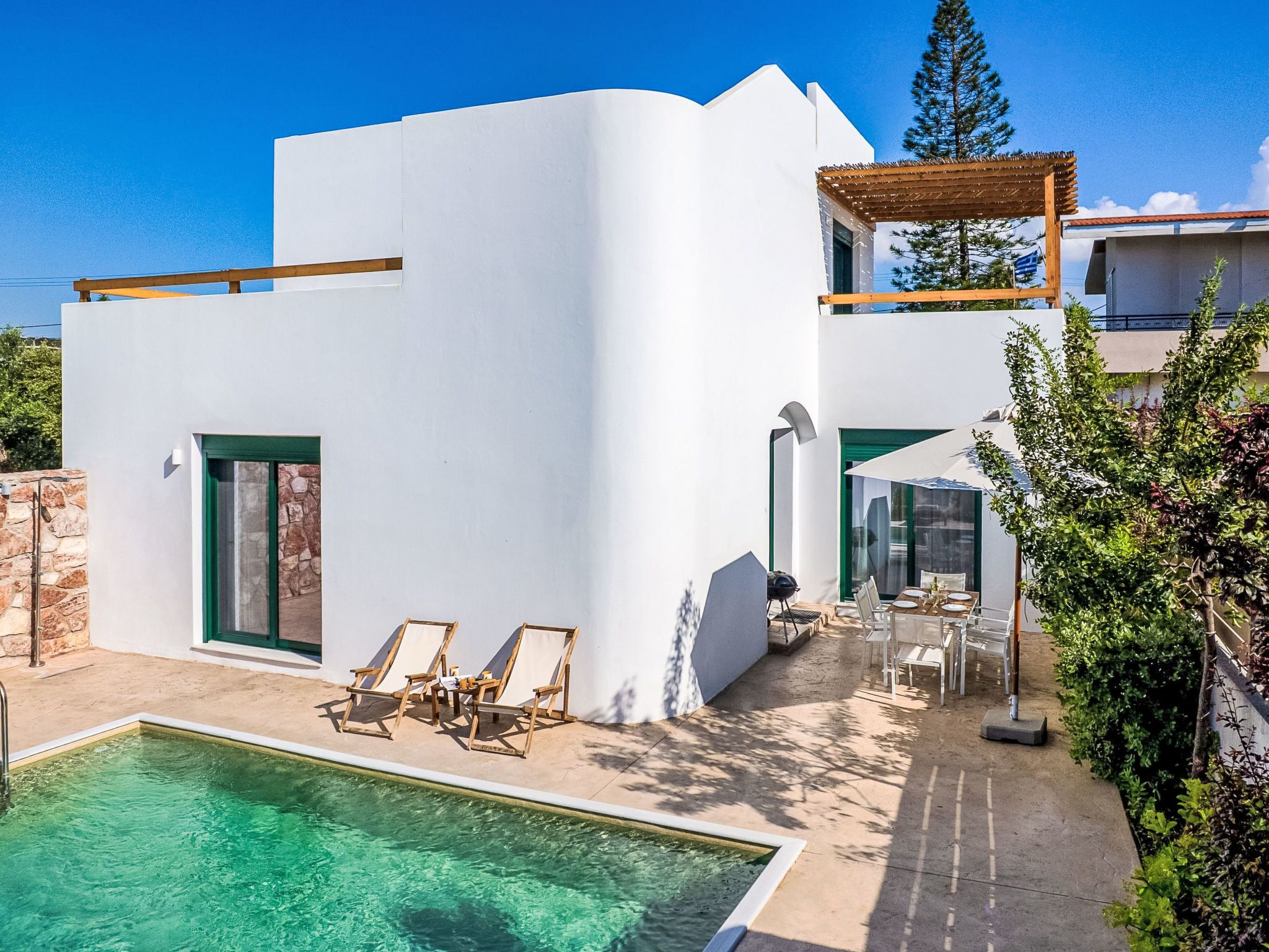 Ein modernes, weißes Gebäude mit Pool, Sitzgelegenheiten im Freien und einer Pergola.