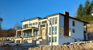 Ein modernes, zweistöckiges Gebäude mit Balkon, Garage und einer Treppe, die zum oberen Stock führt.