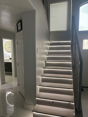 A staircase with a handrail, a door with a light switch, and a window with blinds. - Pretty cozy house with 4 bedroom in northwest Las Vegas, single family home (Las Vegas)