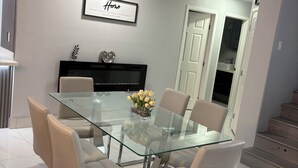 Un coin repas moderne avec une table en verre, six chaises, un vase décoratif et un panneau encadré accroché au mur.