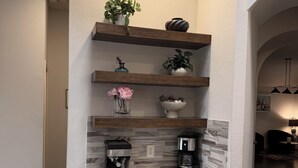 A kitchen with white cabinets, two coffee makers, and shelves with plants. -     Corporate Friendly Frisco Home Fast WiFi Office Near Major Headquarters (Frisco)